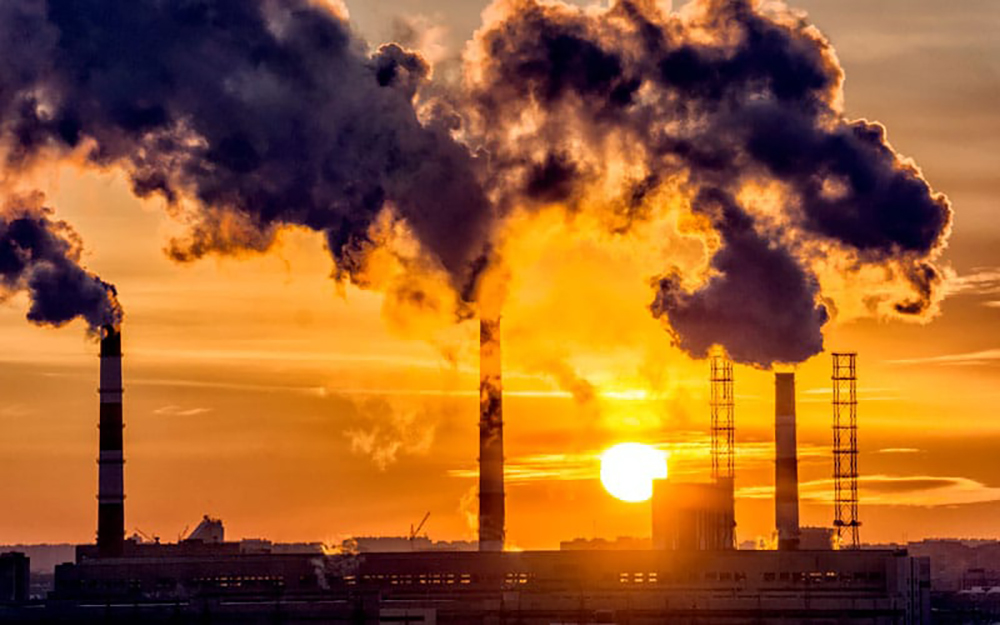 Fotografia de un atardecer contrastado con la contaminación producida por las fabricas en un complejo industrial