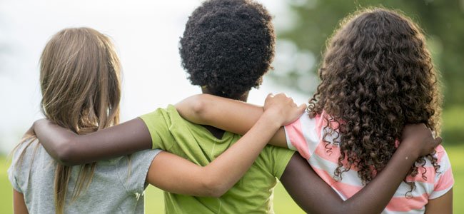 Fotografía de espalda de niños y niñas abrazados,